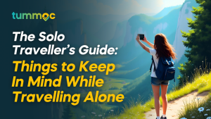 A girl standing on a scenic place with a backpack holding a phone in her hand clicking pictures. The text overlay reads 'The Solo Traveller’s Guide: Your Ultimate Travel Buddy,' along with the Tummoc logo in the top left corner."